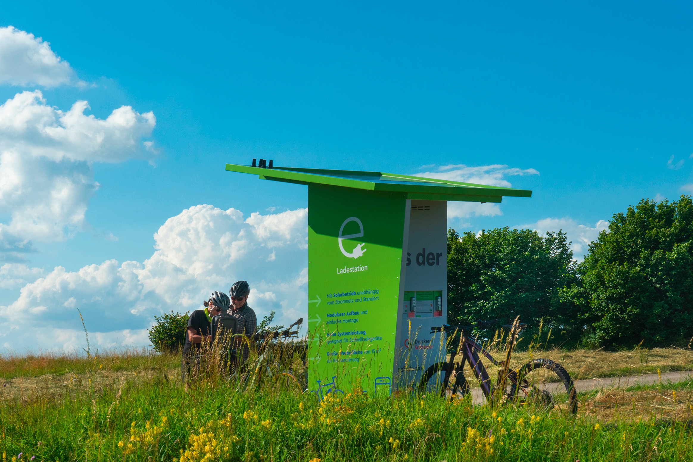 e-Ladestation steht auf dem freien Feld mit zwei Fahrradfahrer
